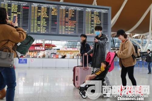 旅客帶著孩子前往辦票柜臺辦理登機手續(xù)?！∫罅⑶?攝