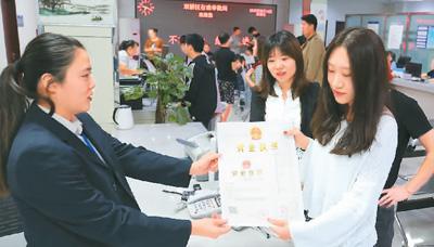 河北省承德市網(wǎng)絡代購經(jīng)營者陳晨(右)從工作人員手中接過帶有統(tǒng)一社會信用代碼的營業(yè)執(zhí)照。 劉環(huán)宇攝(人民圖片)