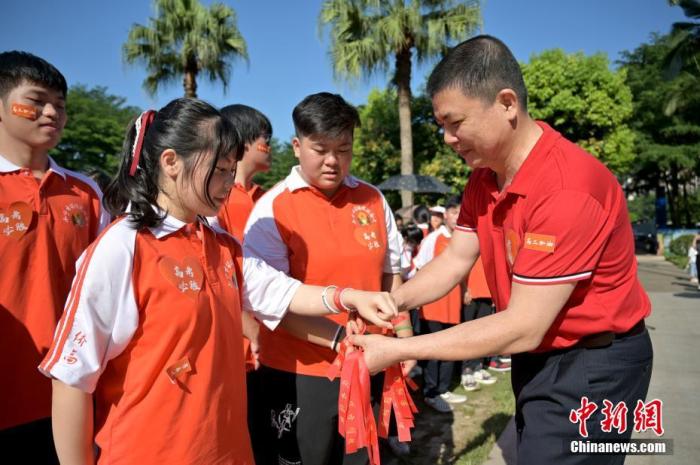 資料圖：廣西華僑實(shí)驗(yàn)高中的教師為高三學(xué)子系上紅絲帶，盼望學(xué)子高考必勝。 俞靖 攝