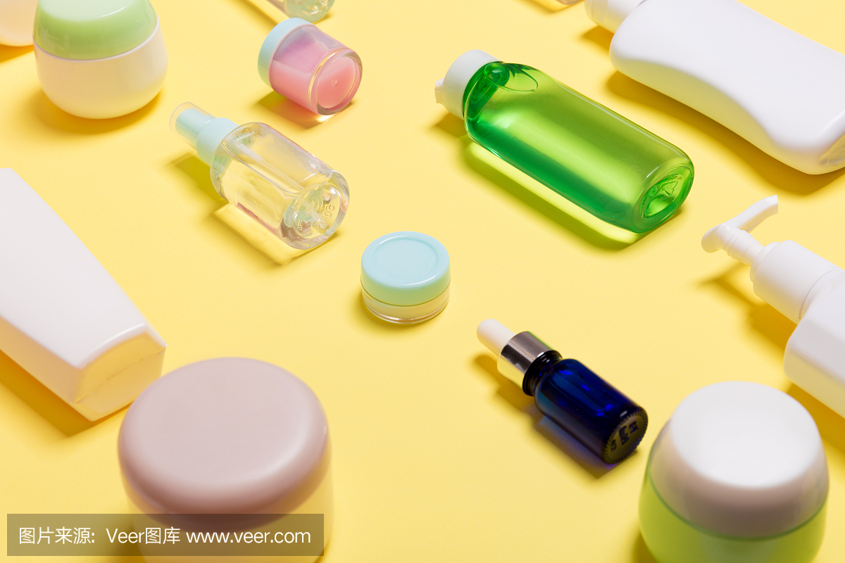 不同大小的化妆品罐和瓶子的组成在黄色的背景。具有复制空间的美容护理理念